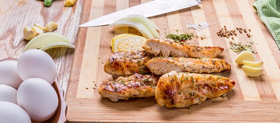 grilled barbecue chicken breast on a baboo cutting board on a  wooden old table